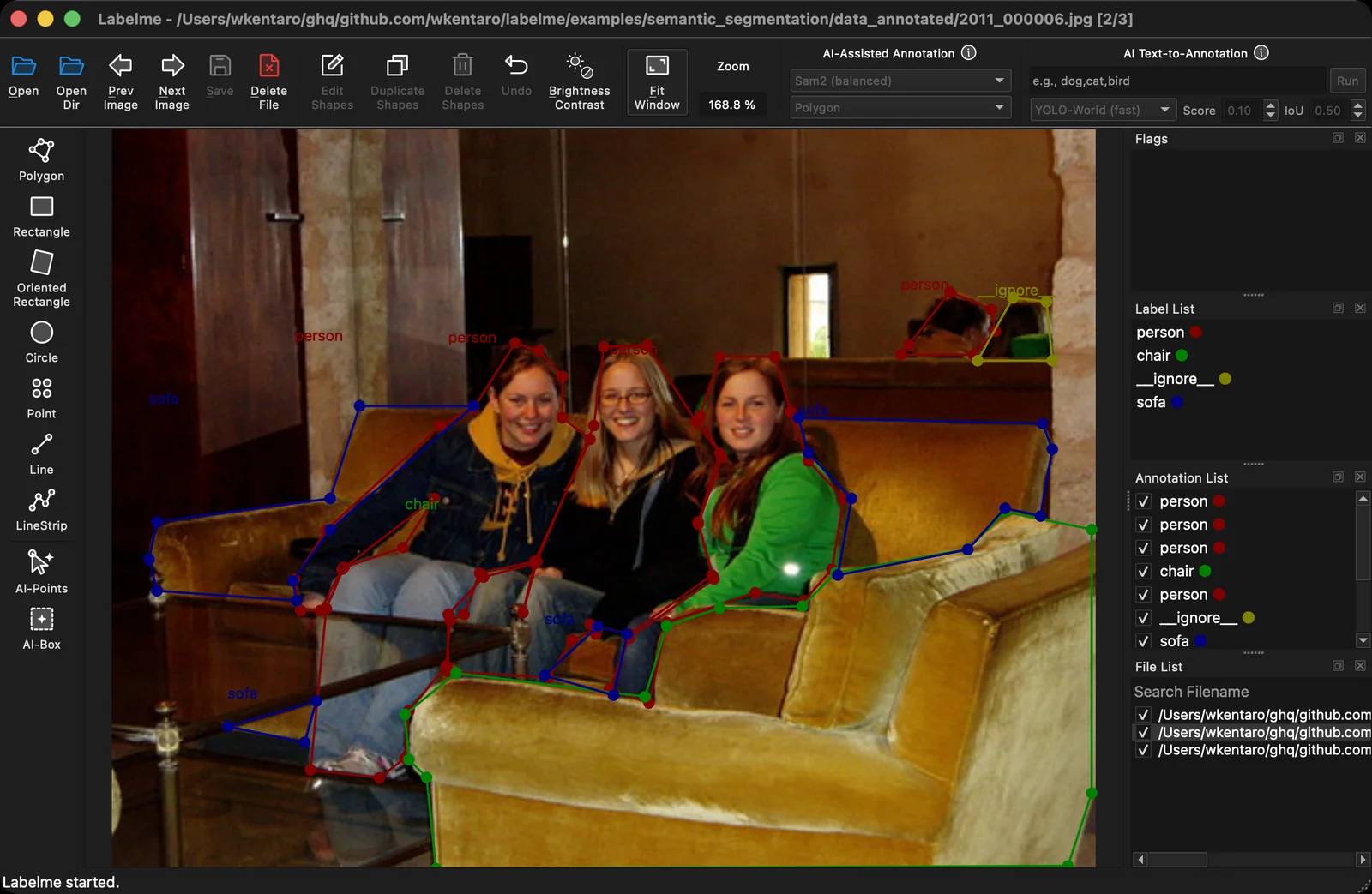 LabelMe v7 in dark mode: a dark title bar, toolbar, and side panels, annotating a photo of three people on a sofa with polygon shapes